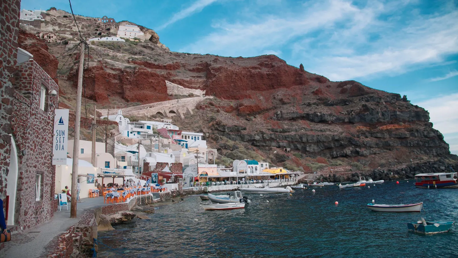 Ammoudi Bay below Oia: fishing boats and tavernas under the red cliff