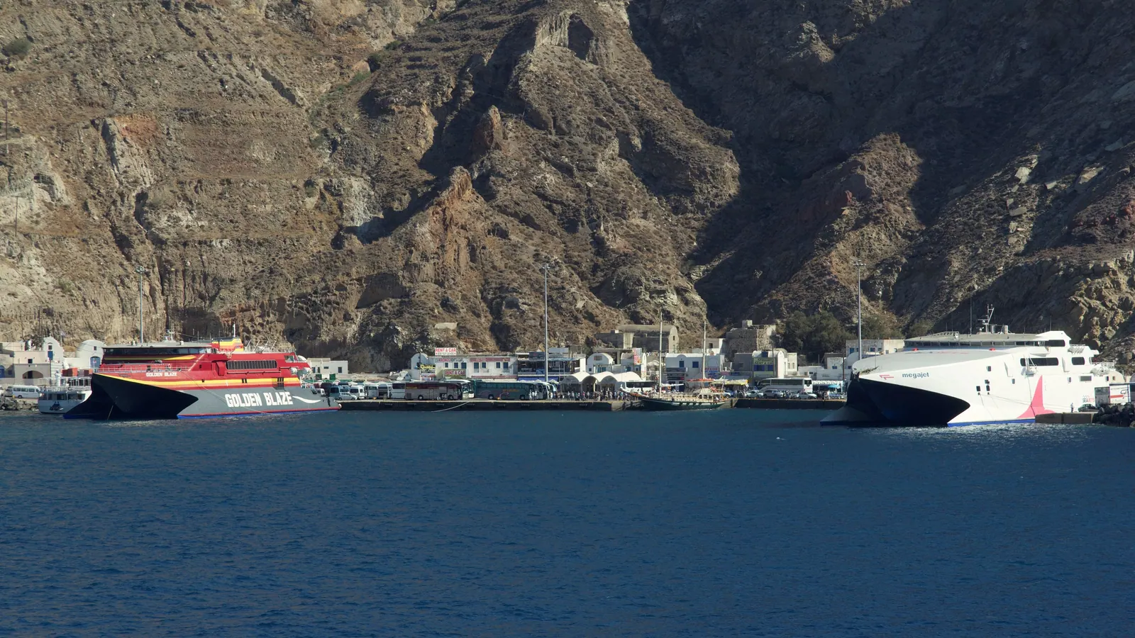 Ferries at the pier of Athinios port under the caldera cliff