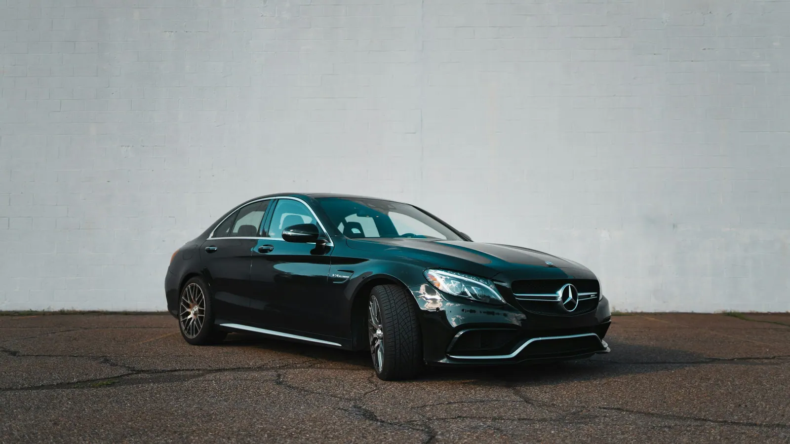 A black Mercedes saloon against a plain wall, the class used for up to four passengers