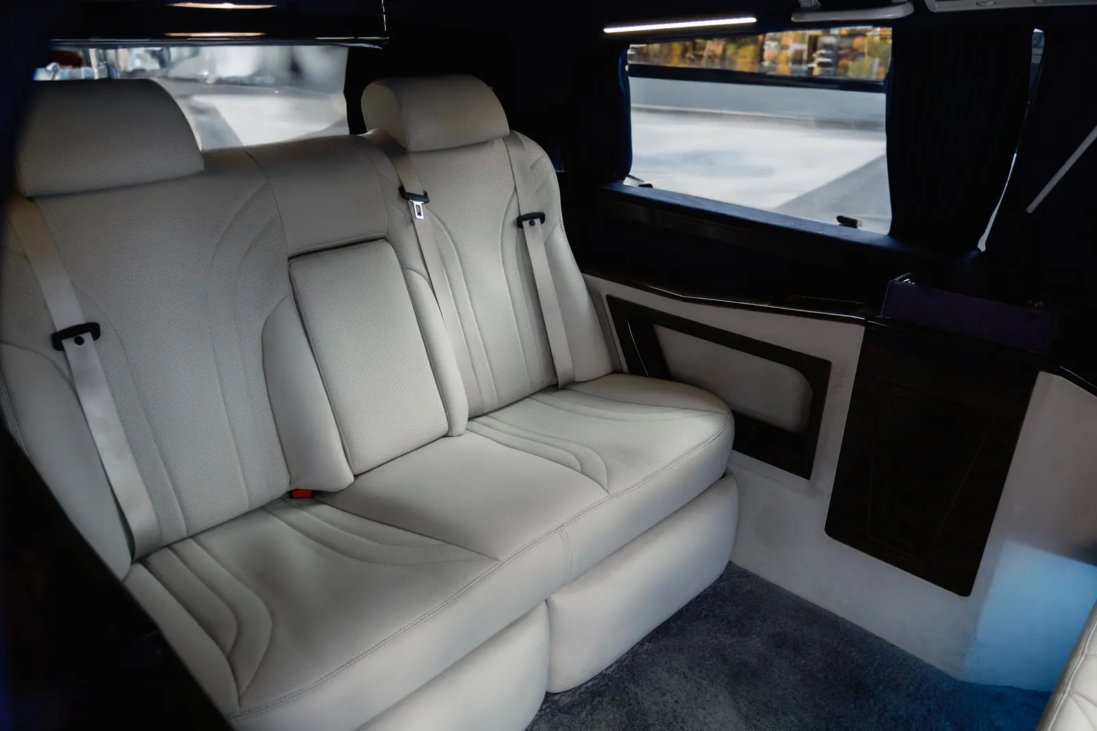 The cabin of a luxury Mercedes van with cream leather seats, the class used from the fifth passenger
